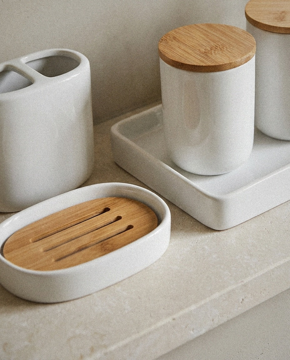 Close-up of white ceramic jars with bamboo lids, tray and bamboo soap dish