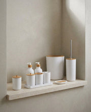 White 9-piece ceramic bathroom accessory set with bamboo lids on a stone ledge
