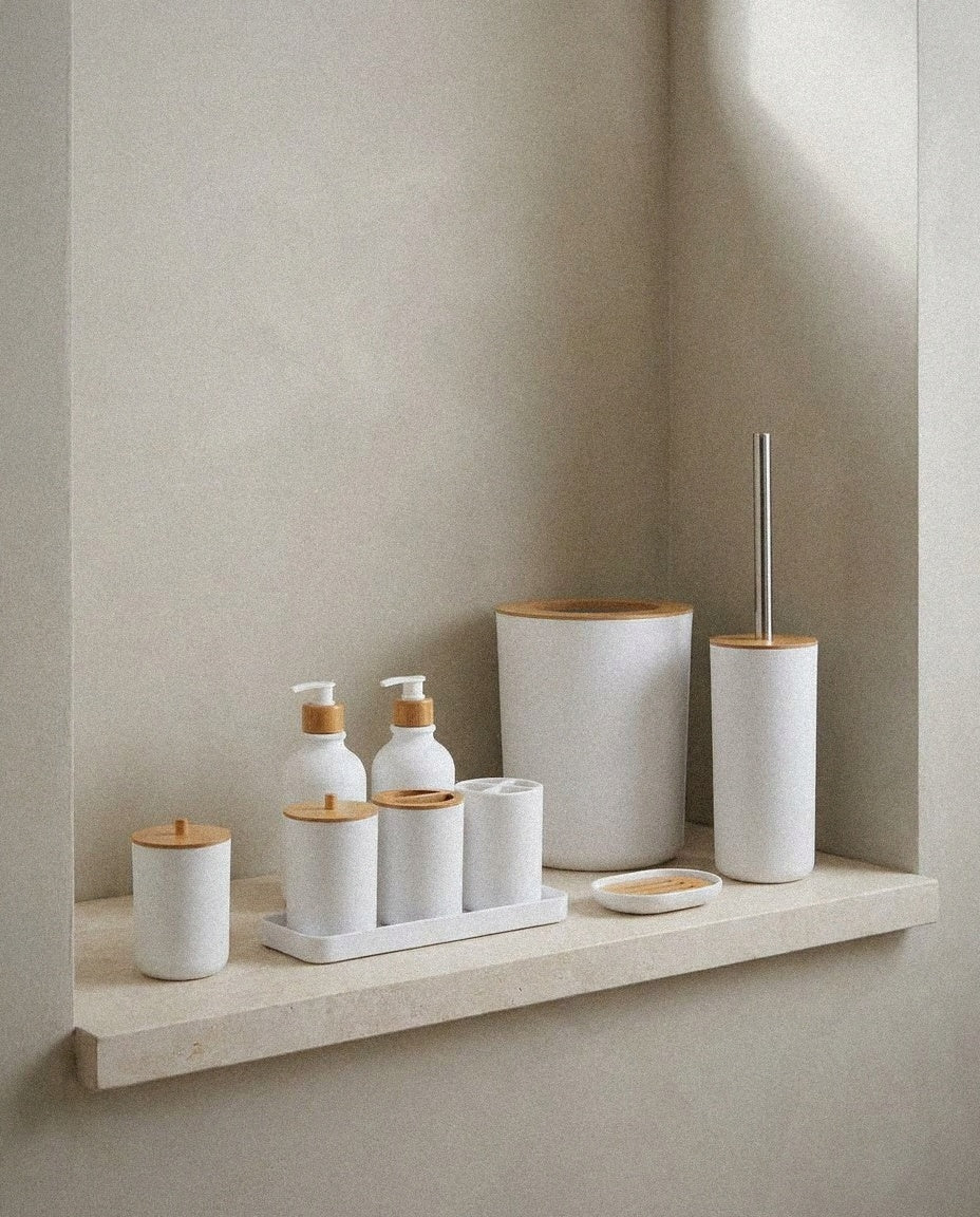 White 9-piece ceramic bathroom accessory set with bamboo lids on a stone ledge