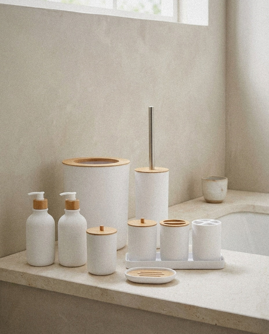 White ceramic bathroom set with dispensers, jars, bin and toilet brush beside a basin