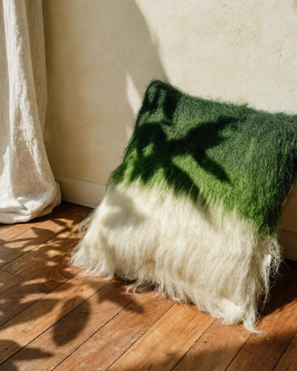 Emerald green handwoven wool pillow in mid-century modern interior, soft daylight, editorial still life