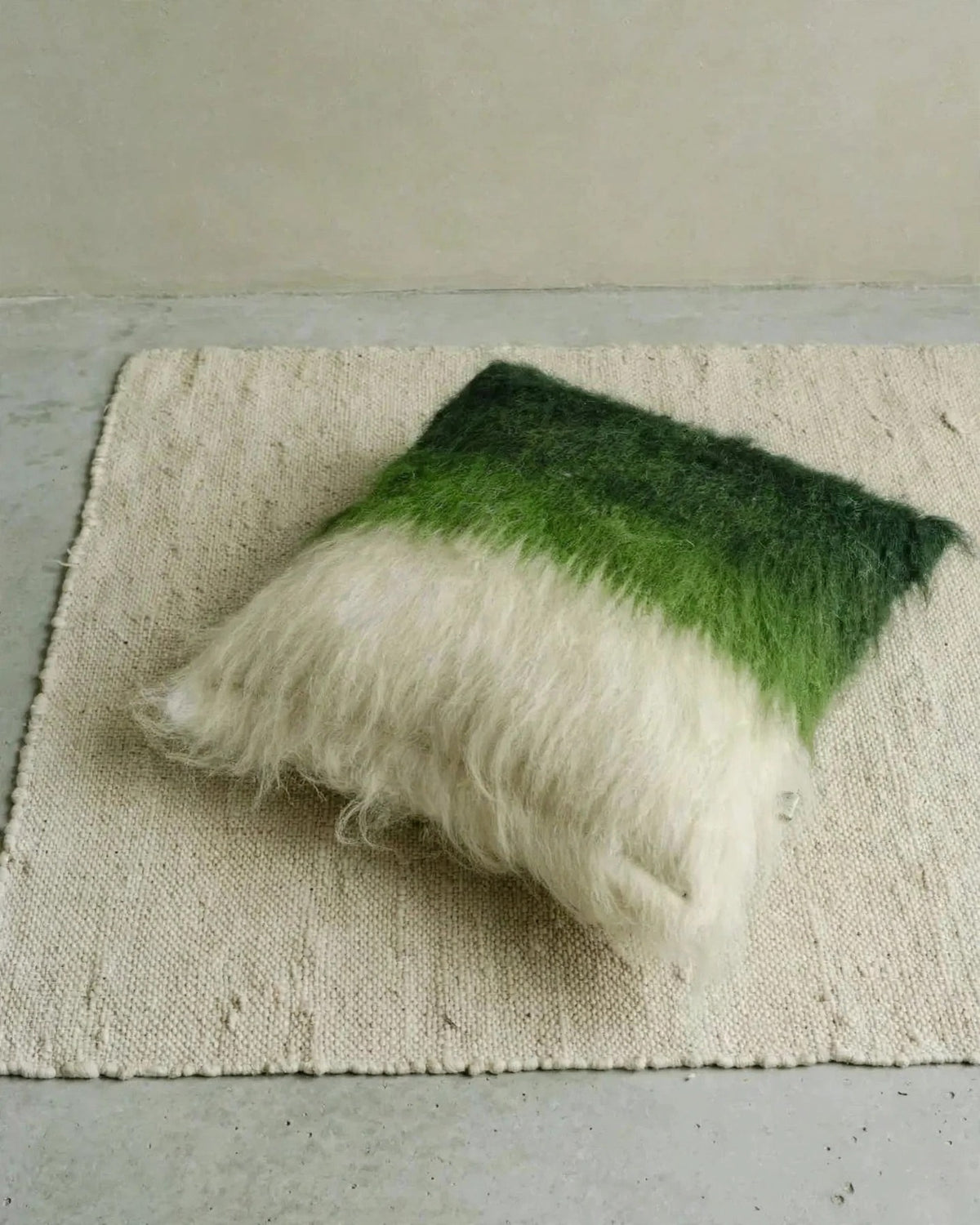 Emerald green handwoven wool pillow in organic modern interior, soft daylight, editorial still life