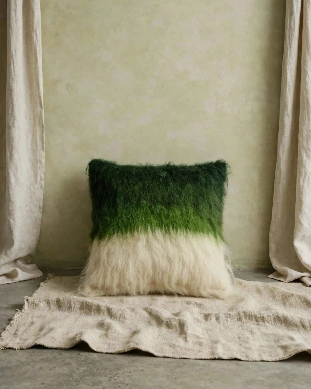 Emerald green handwoven wool pillow in organic modern interior, soft daylight, symmetrical product shot