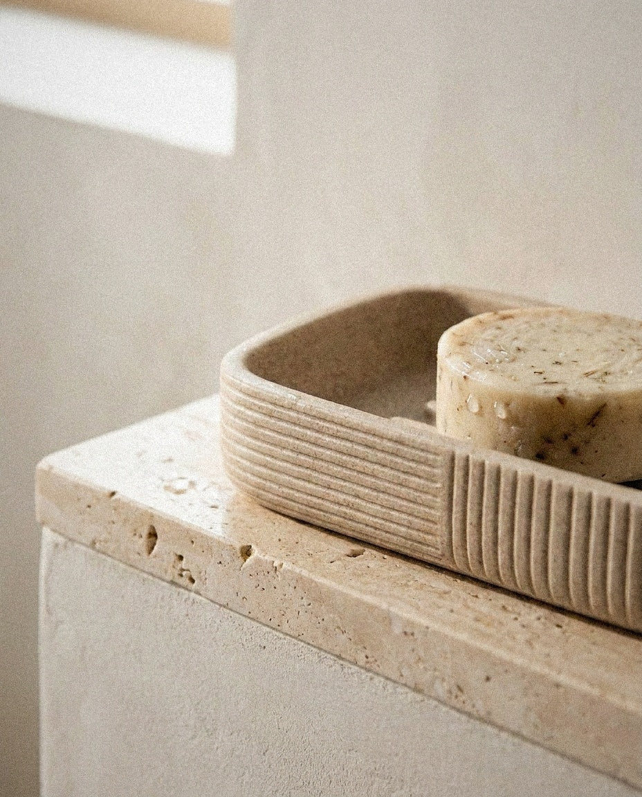 Close-up of the fluted beige ceramic soap dish with a natural soap bar