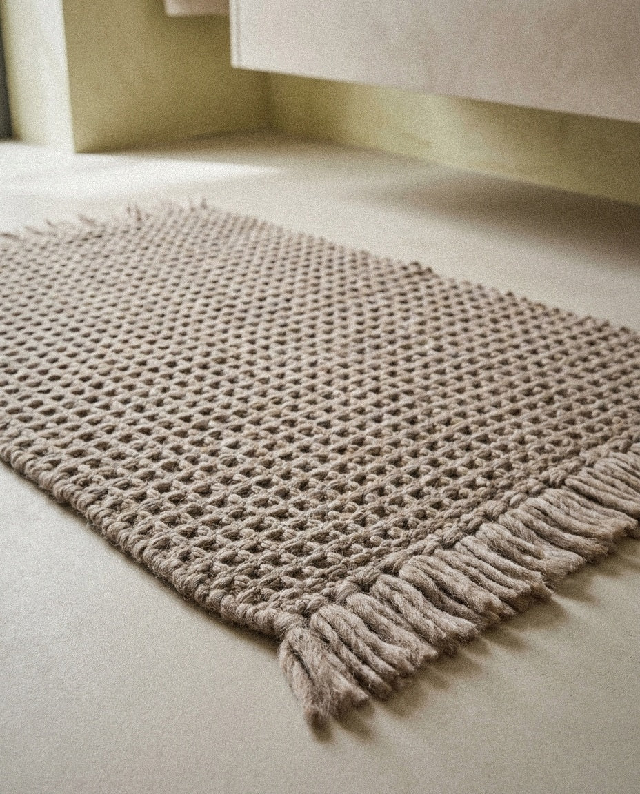 Close-up of the handwoven waffle texture and soft fringe of the Siena bath mat
