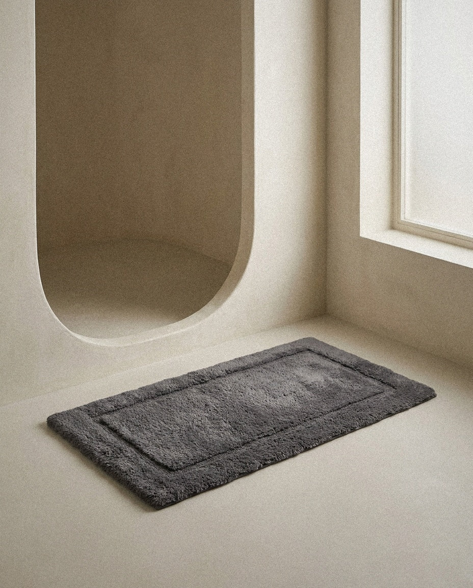 Charcoal UltraPlush cotton bath mat on a microcement bathroom floor
