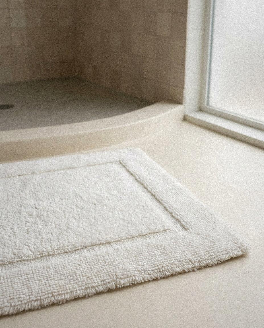Close-up of the dense plush cotton pile and border of the white bath mat