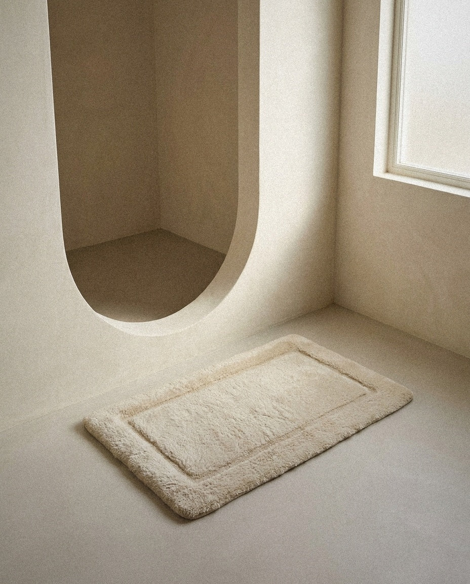 Sand UltraPlush cotton bath mat on a microcement bathroom floor