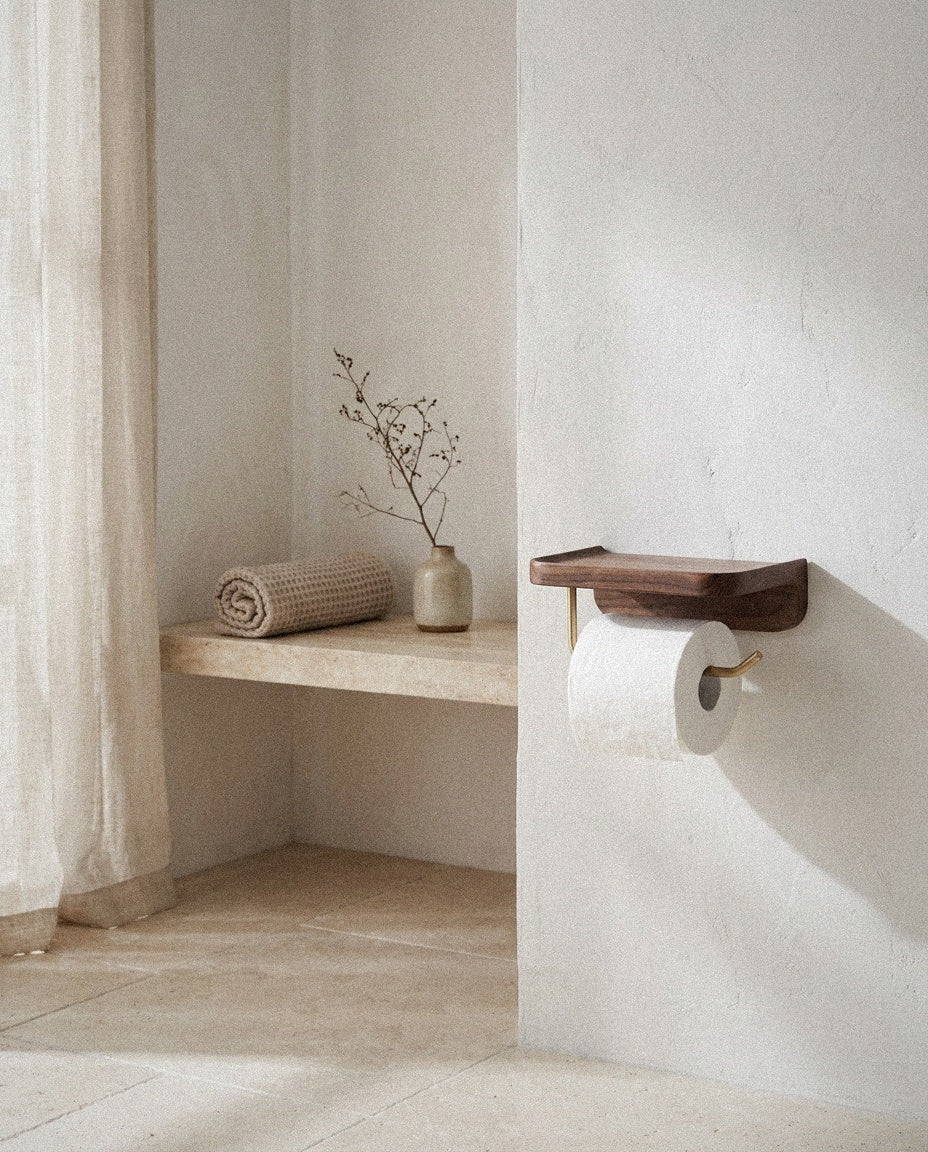 Wall-mounted wood toilet roll holder with shelf in a bright stone-floored bathroom